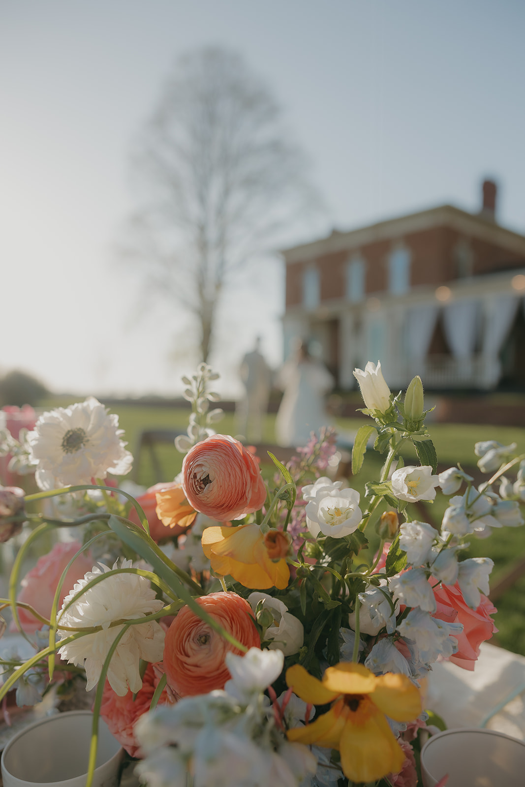 Close-up of ranunculus and spring florals with historic venue in the background, old money wedding florals
