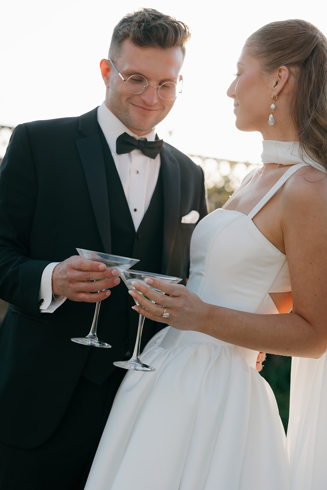 Bride and groom toasting with martini glasses at sunset, old money wedding reception
