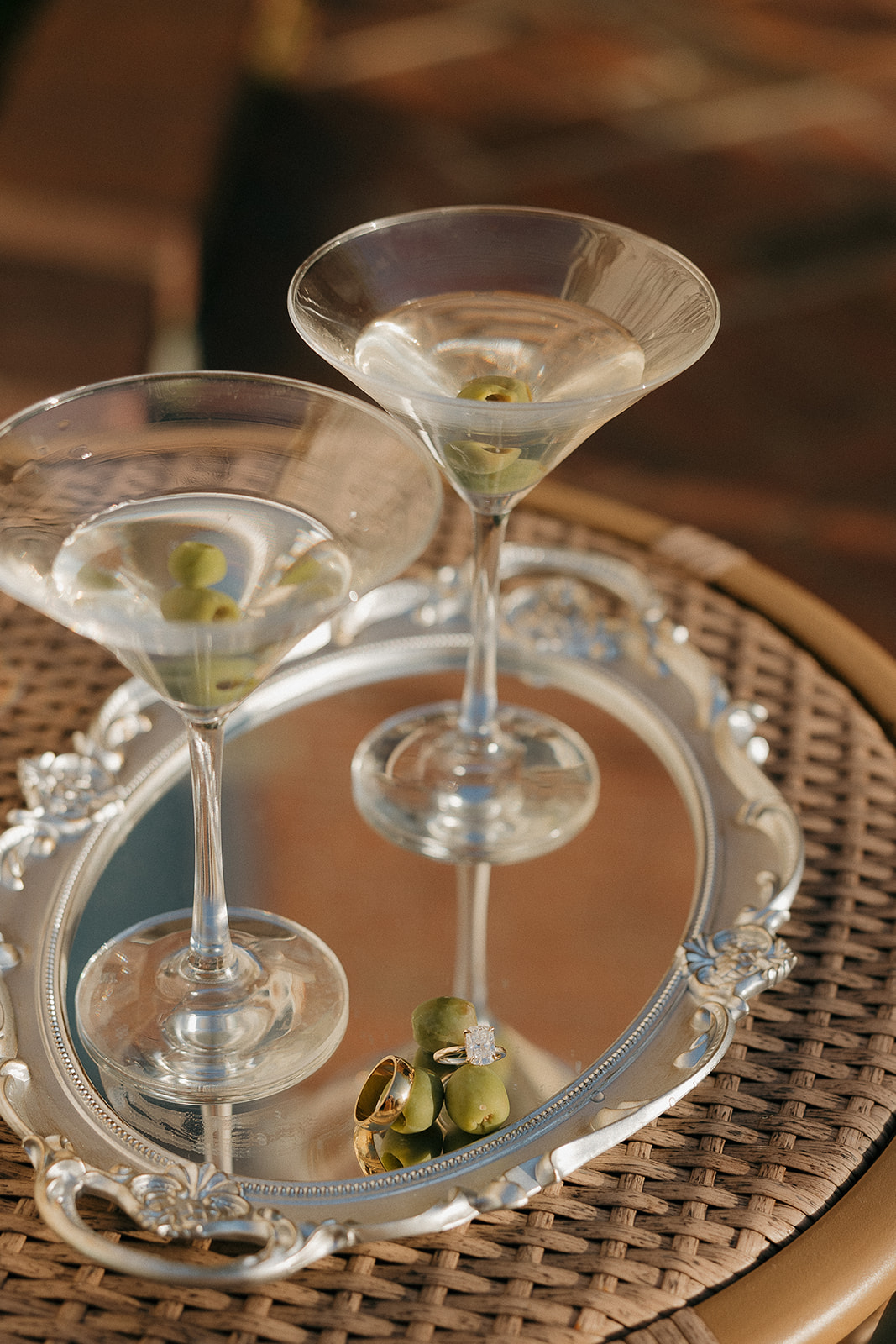 Two martinis with olives and wedding rings on a silver mirrored tray, old money wedding details done to perfection
