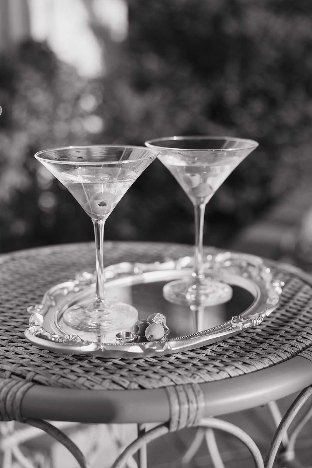 Two martini glasses with wedding rings on a silver tray
