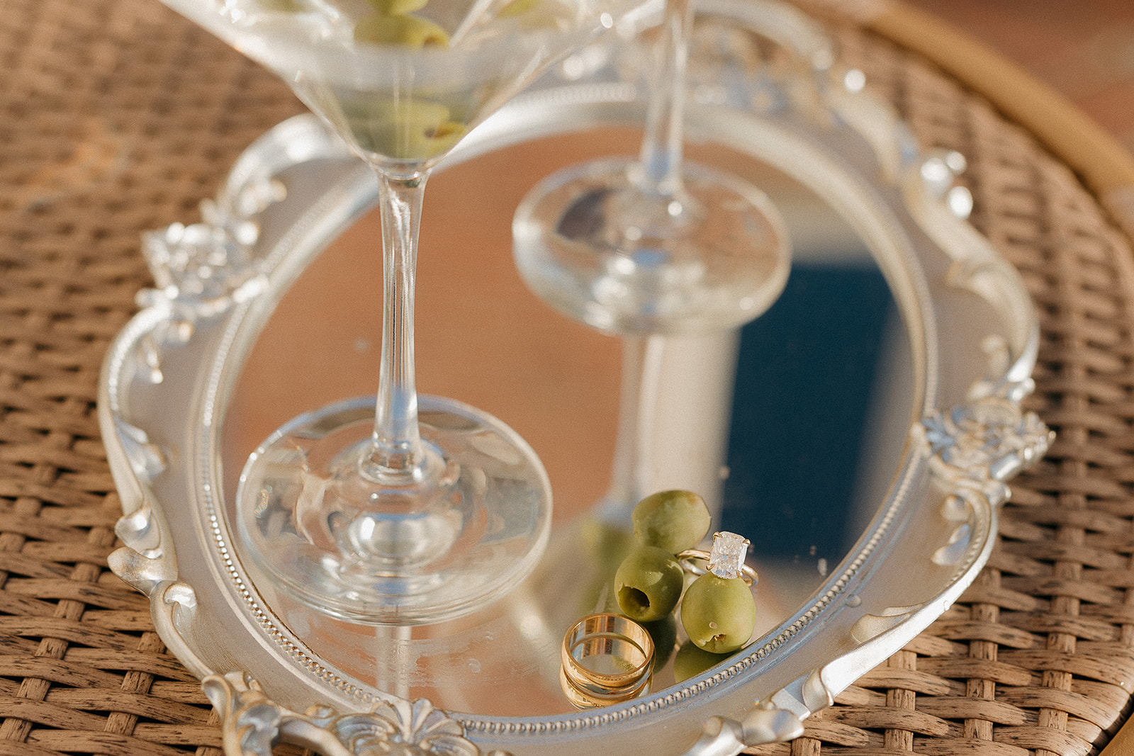 Wedding rings and olives on a silver mirrored tray beside martini glasses, old money wedding details
