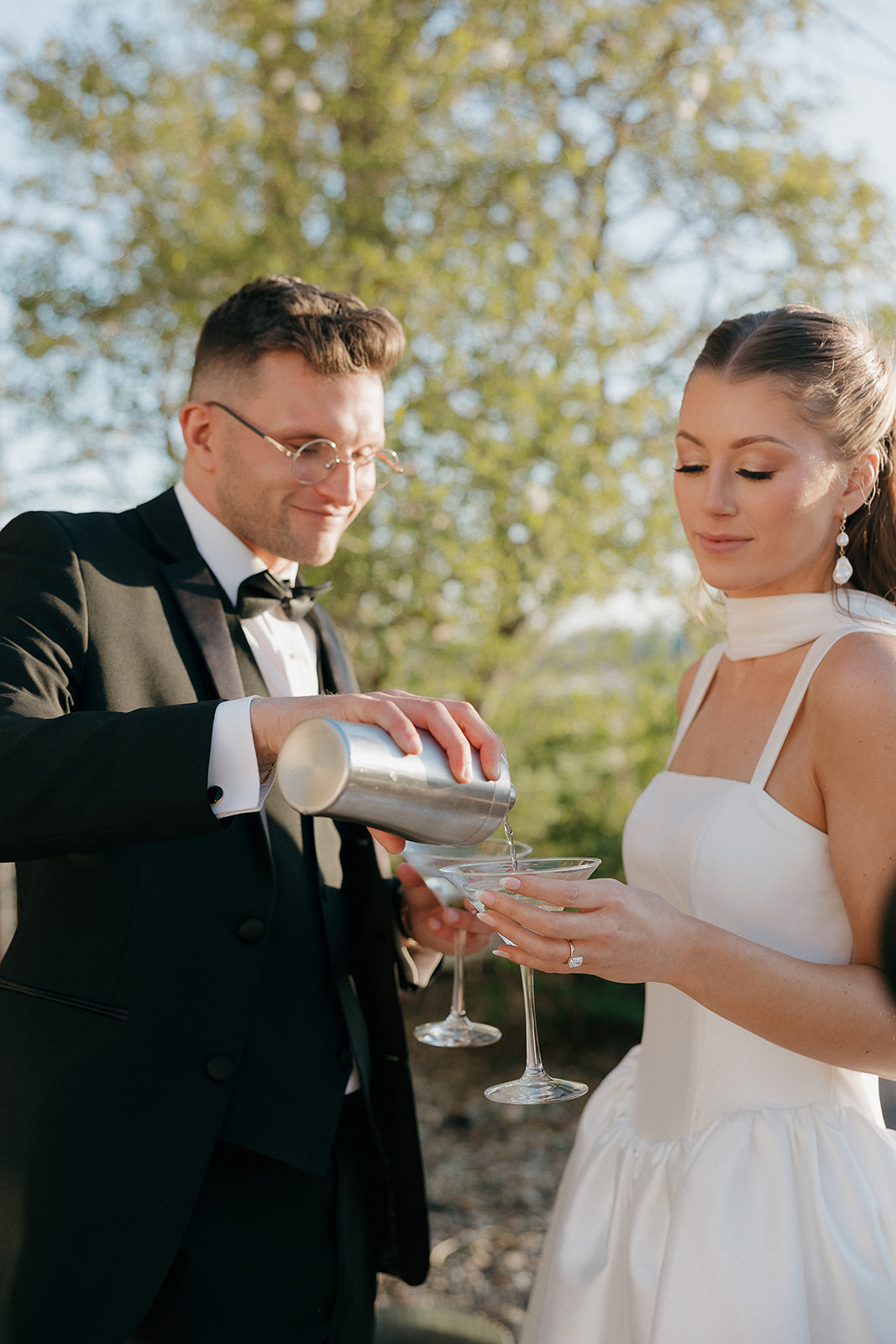 Groom pouring a martini for his bride in golden hour light, an effortlessly elegant old money wedding moment
