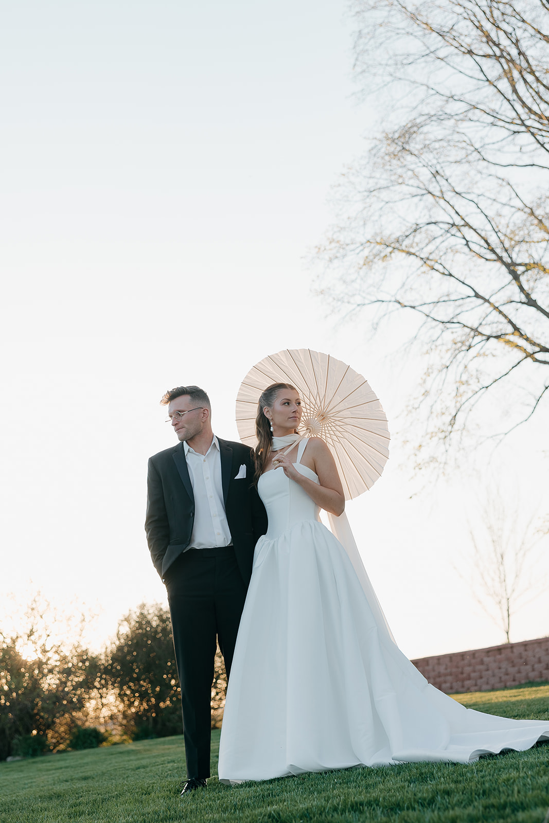 Bride and groom posing with a white parasol at golden hour, old money wedding portraits
