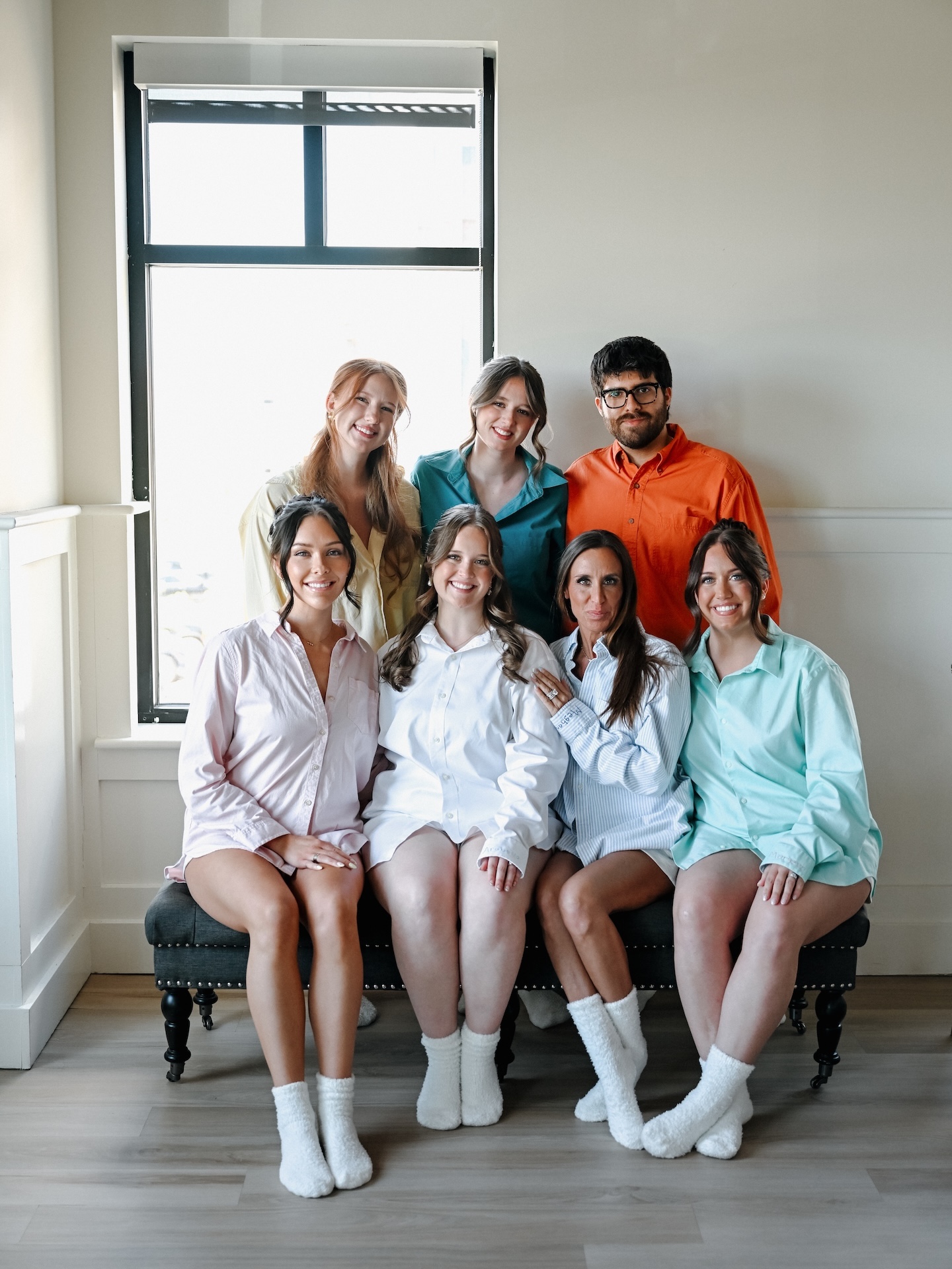 The bridal party poses together in colorful button-down shirts and white fuzzy socks during getting-ready photos
