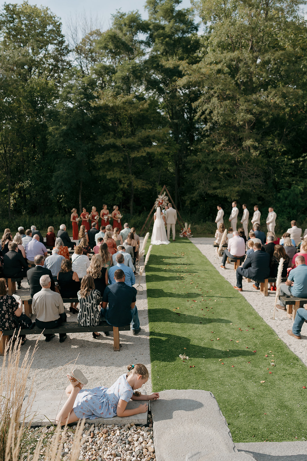 Wide aerial view of the wedding ceremony with guests seated on either side of the aisle in fall wedding colors