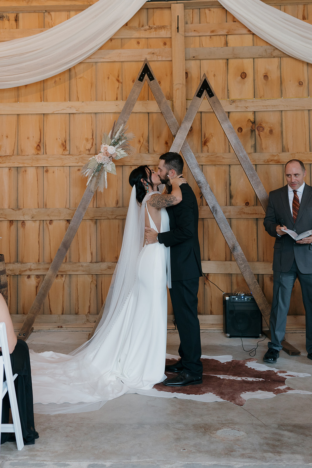 Bride and groom's first kiss at the altar framed by rustic wooden mountain peak decor