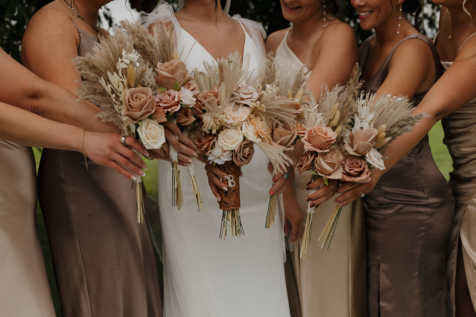 Close up of the full bridal party's boho bouquets in blush, rust, and cream tones