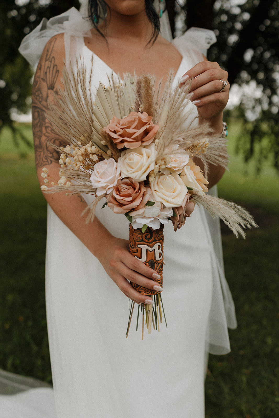 Close up of bride's dried pampas grass and rose bouquet with a leather wrapped monogram holder, a favorite fall wedding detail