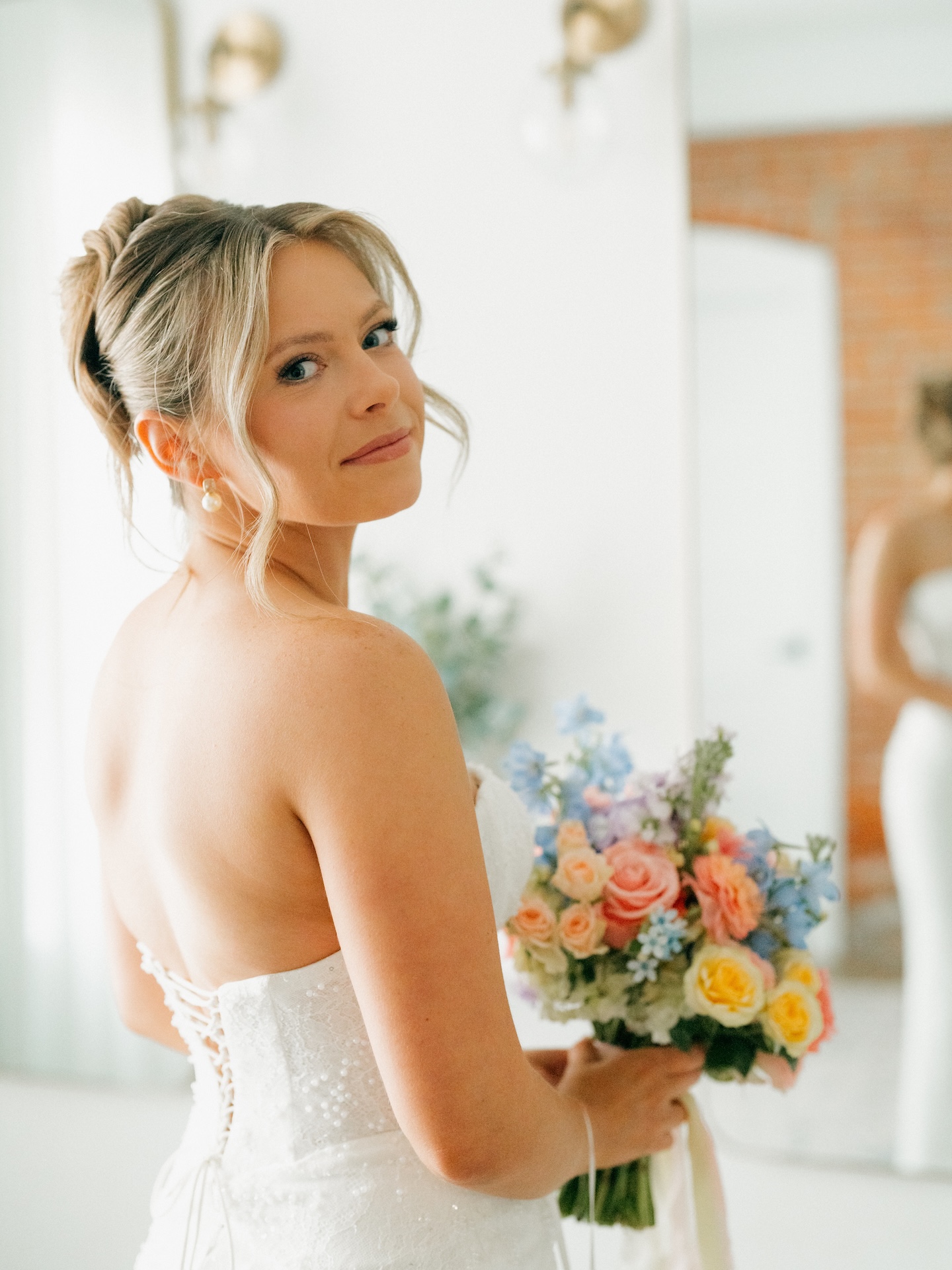 Bride glancing over her shoulder while holding her colorful wedding bouquet during getting-ready portraits.