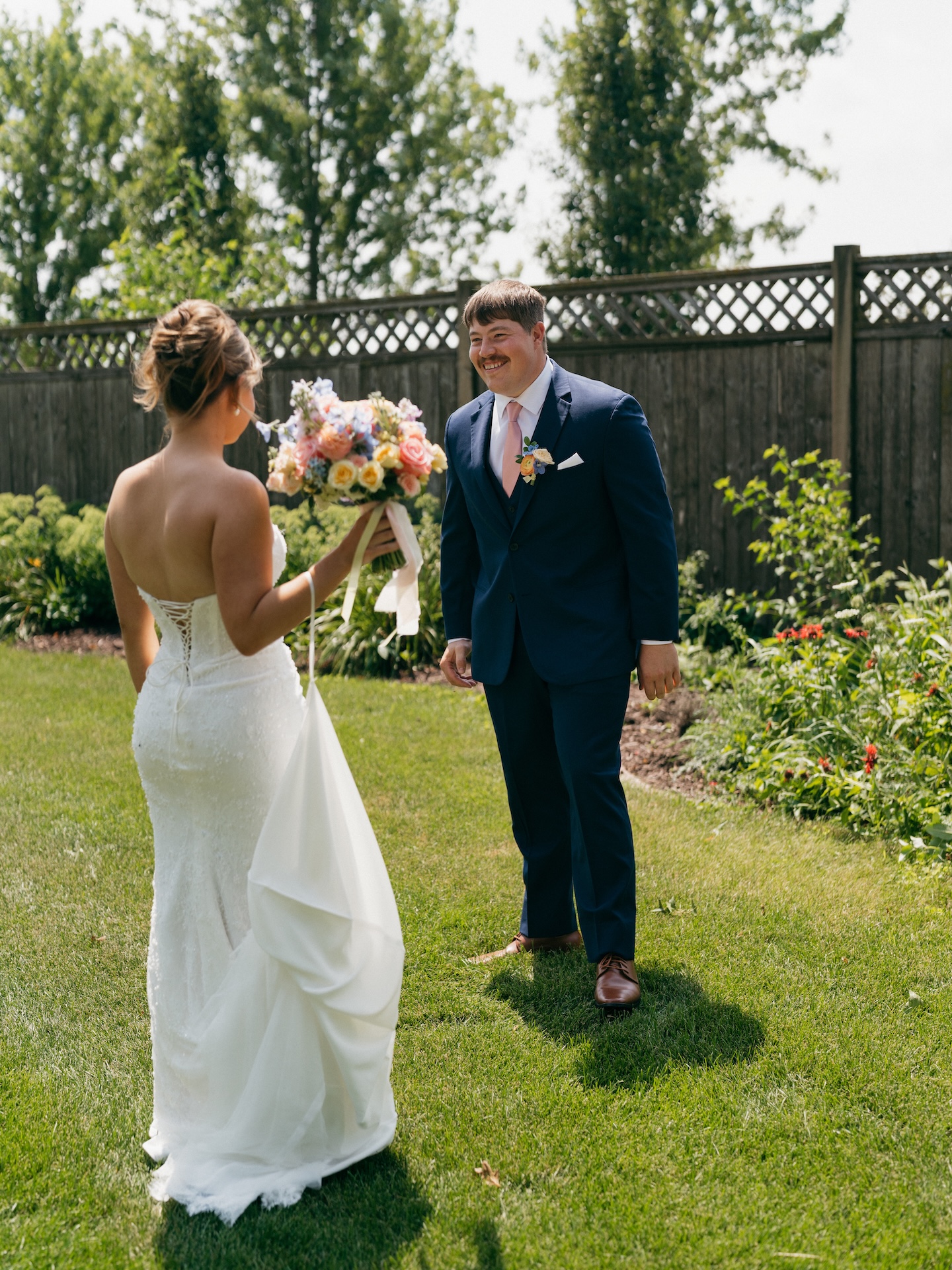 Groom smiling as he sees his bride for the first time during their backyard first look.