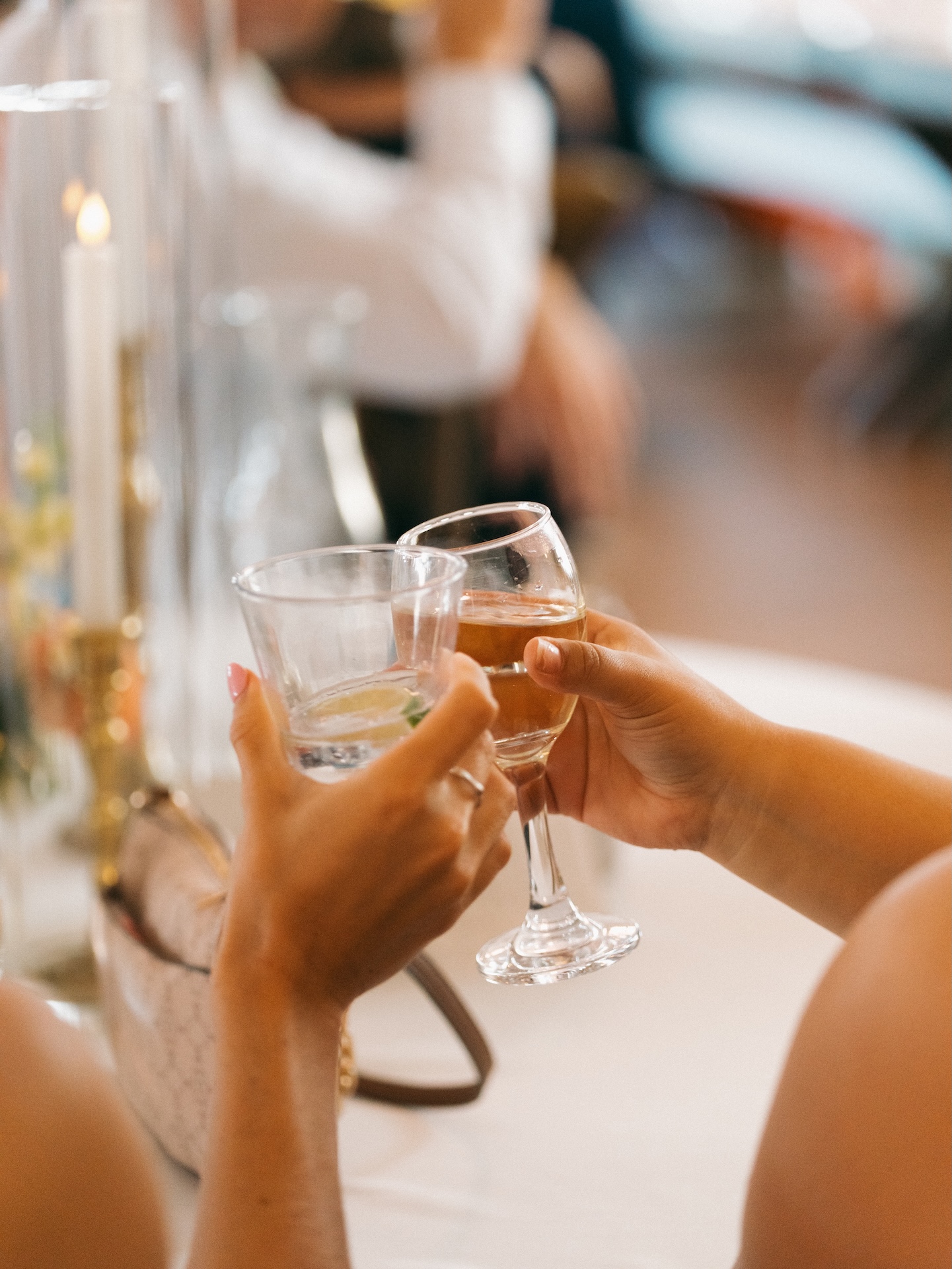 Guests clinking a cocktail and a glass of beer together during the wedding reception toast.
