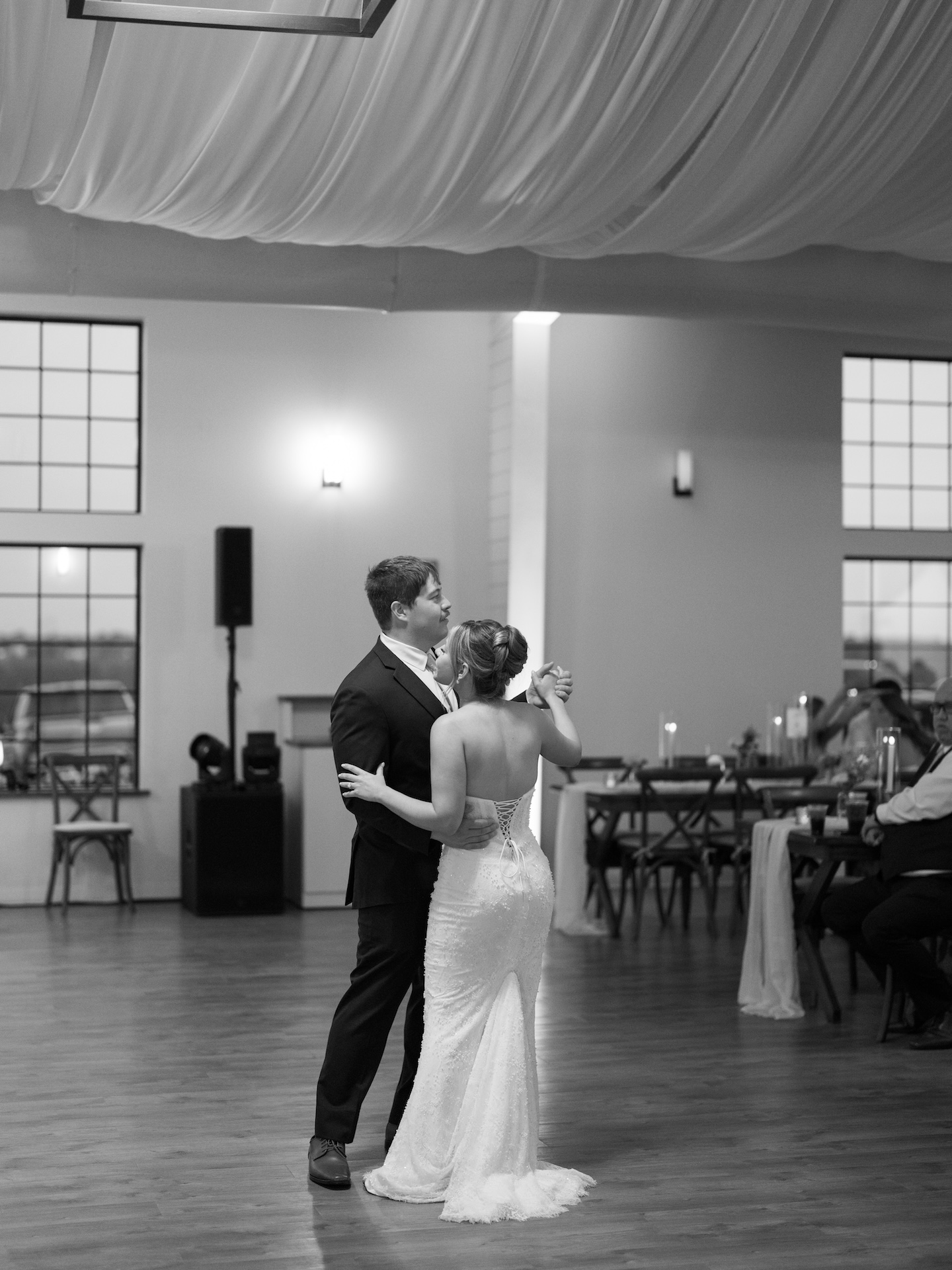 Black and white photo of the bride and groom sharing their first dance in the reception hall.