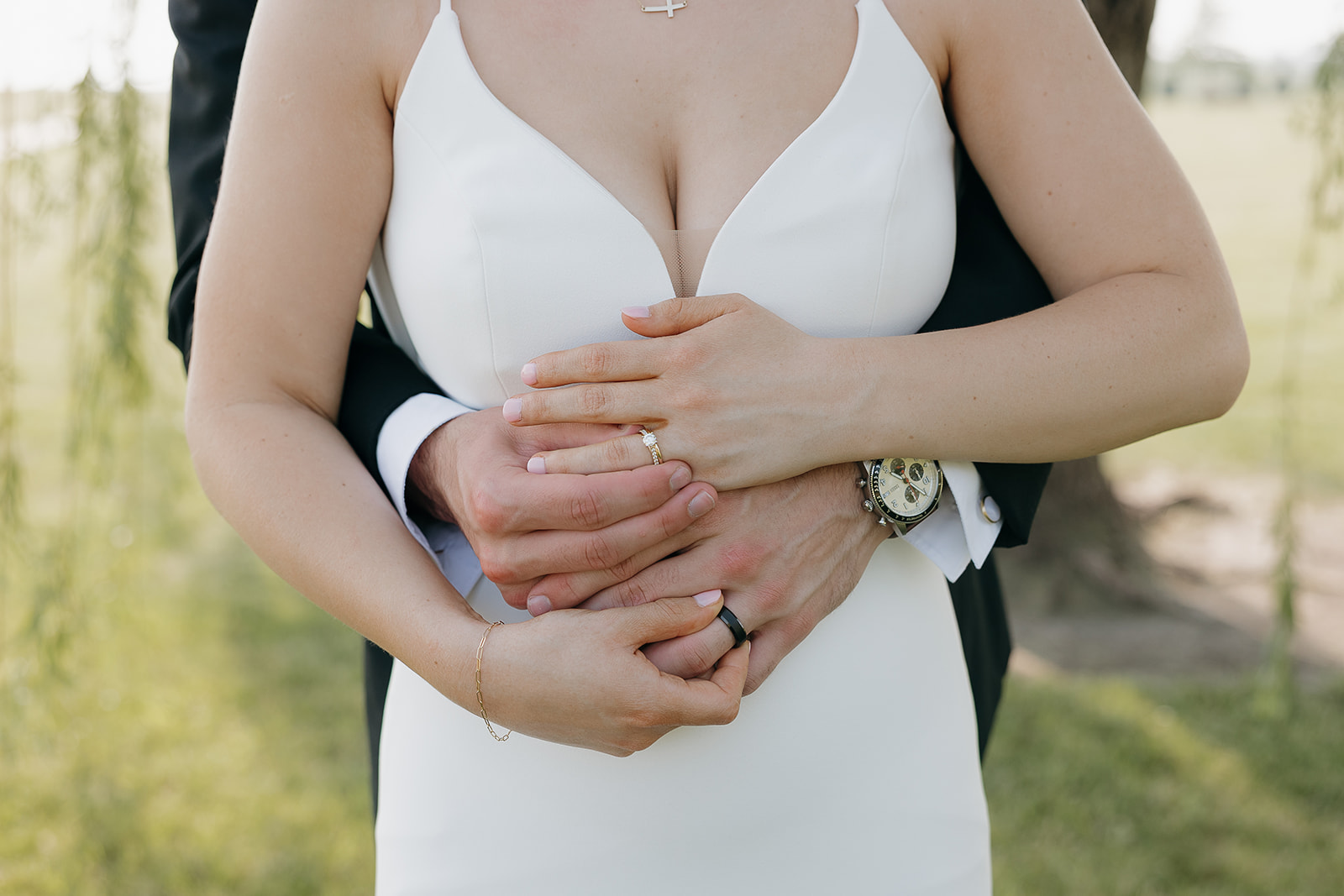 Close up detail shot of the bride and groom's hands showing their wedding rings and watch.