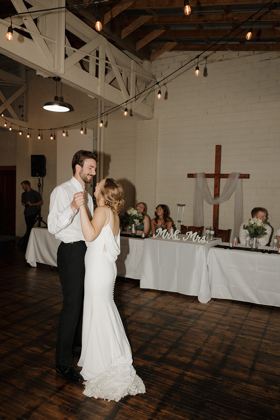 Bride and groom sharing their first dance together as guests look on from the head table at this modern wedding venue (Highpoint Event Center).
