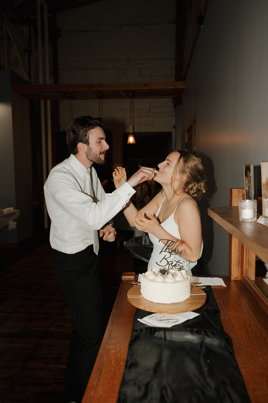 Groom feeding his bride a bite of their wedding cake at the reception.