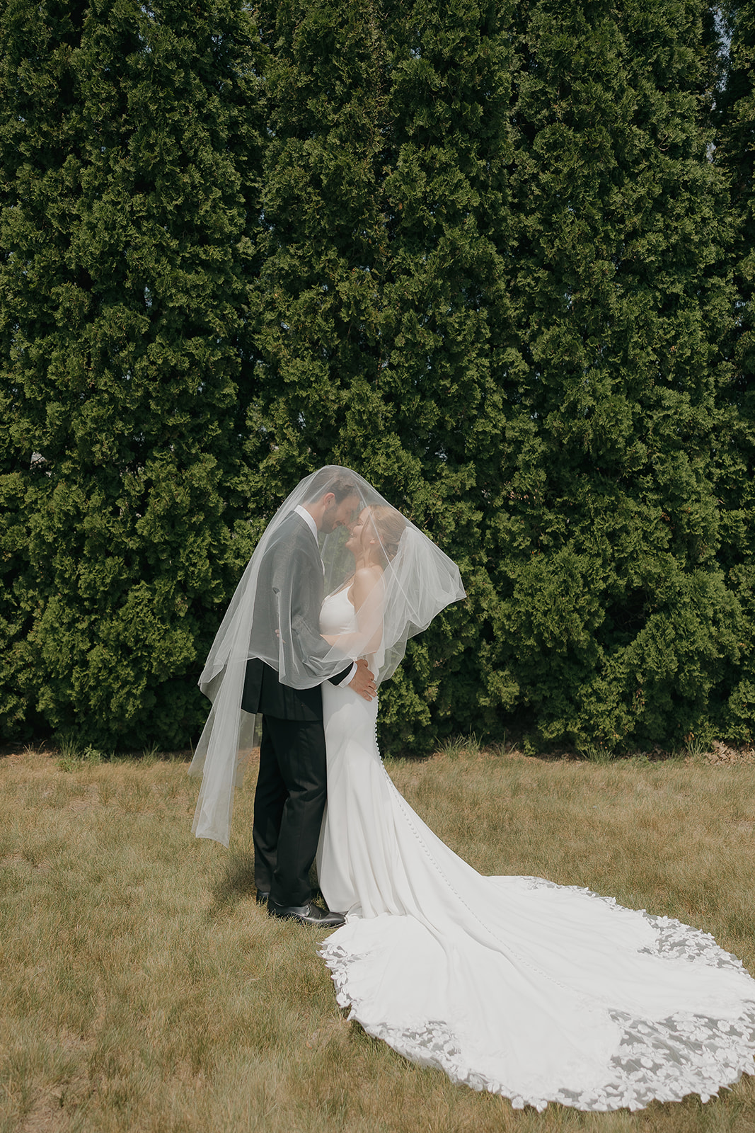 Bride and groom sharing a kiss hidden underneath her cathedral length veil.